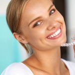 Woman smiling holding invisalign Braces